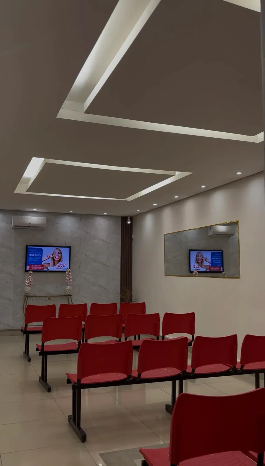 Recepção da Odonto Plus com cadeiras vermelhas e ambiente novo